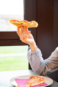 Person enjoys a pizza slice during lunch break