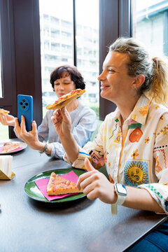Women enjoying lunch break with pizza in cafe