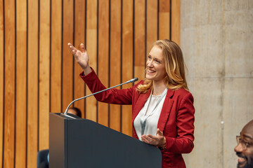 Plakat Woman business speaker giving confident conference presentation at podium with microphone