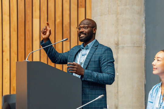 Business conference speaker giving a confident presentation at podium in modern meeting room
