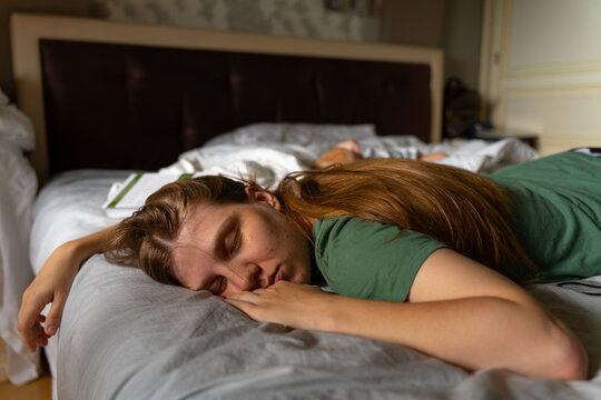 Tired woman resting on bed at home with soft daylight