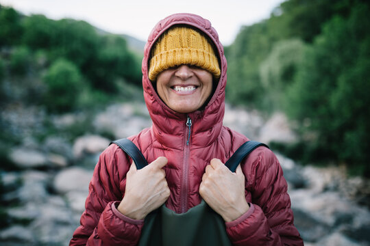 Smiling woman hiker in warm jacket by mountain stream