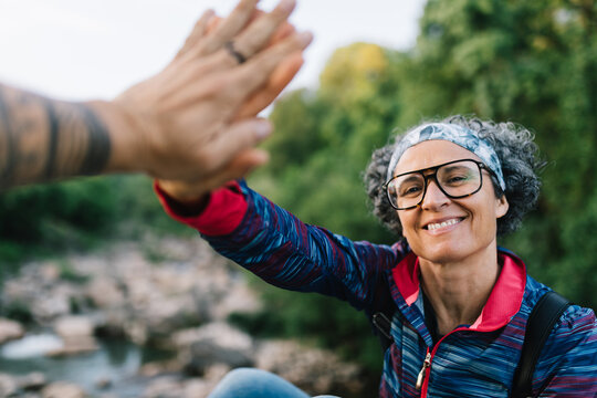 Smiling woman hiker giving high five in green nature