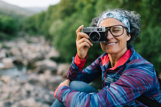Woman hiker taking a photo with camera in nature
