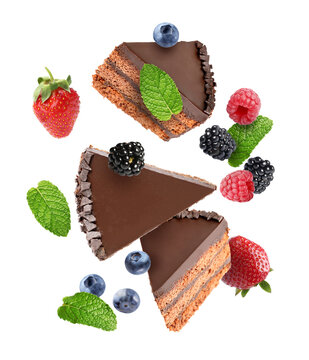 Chocolate cake pieces and fresh berries falling against white background