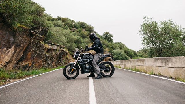 Man on motorcycle stopped on empty mountain road