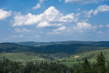 Fototapeta premium Alpine valley landscape with rolling green hills and forest