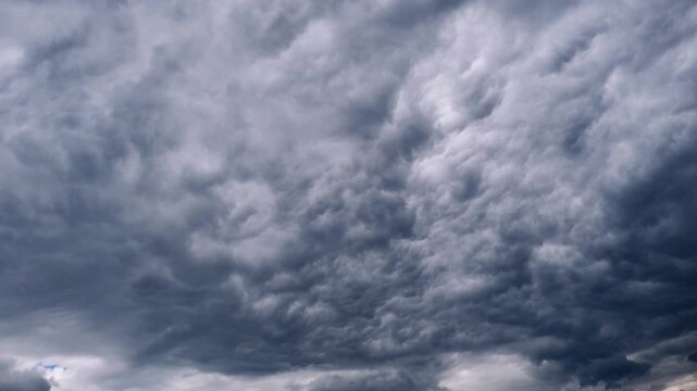 Timelapse records menacing dark grey storm clouds boiling and churning in a seamless loop. The turbulent heavy cloud mass creates an intense apocalyptic atmospheric background.