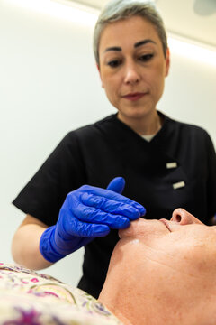 Senior woman receiving facial skin care treatment in spa