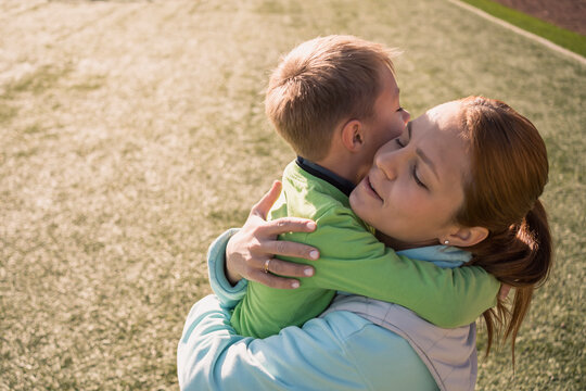 Mother and son embrace outdoors after football game