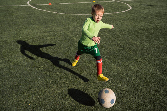 Young boy playing football outside on a sunny day