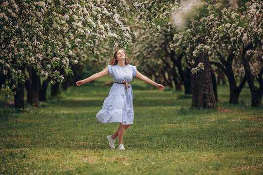 Woman enjoying blooming spring orchard with arms outstretched