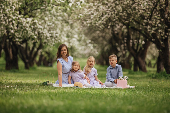 Happy family relaxing in blooming orchard during spring