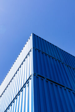 Stacked blue shipping container corner against clear sky