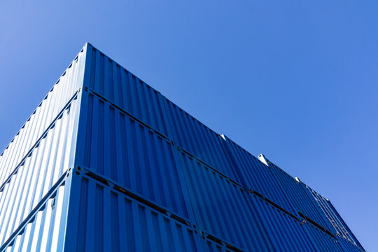 Blue shipping container stack against clear sky background