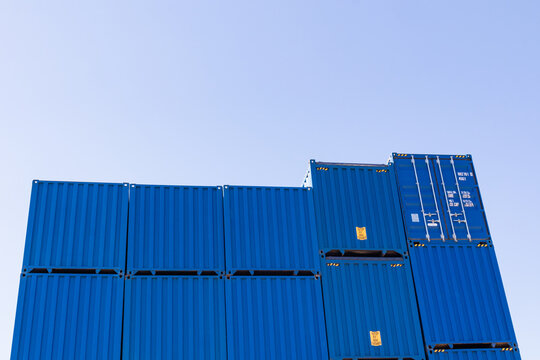 Stacked blue shipping container wall with clear sky