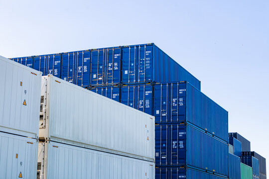 Stacked cargo containers at port terminal under blue sky