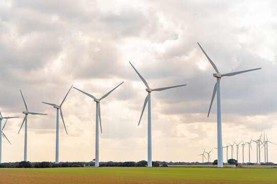 Wind turbine farm on green field under cloudy sky