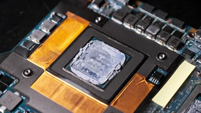 A rotating close-up shows a computer processor chip coated in old, dried thermal paste on a blue circuit board. Concept of hardware maintenance, pc overheating issues, and technical repair.