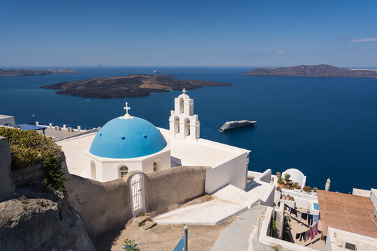 White church with blue dome overlooking Greek island sea