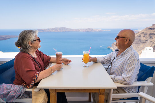 Senior couple enjoying drinks with Greek island sea view