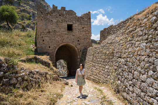 Traveler walking through ancient stone gate in Corinth Greece