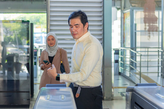 Commuter tapping smart card at subway station entrance gate