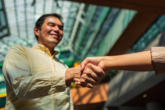 Business handshake in sunlit modern office atrium setting
