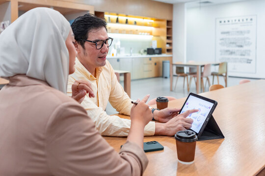 Business colleagues review data on tablet in modern office
