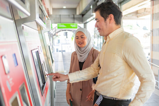 Commuters buying tickets at a transit kiosk on platform