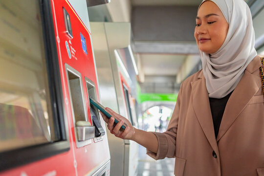 Muslim woman buying metro ticket at station machine