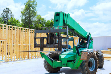 Construction vehicle telehandler lifts wooden trusses beams on building site