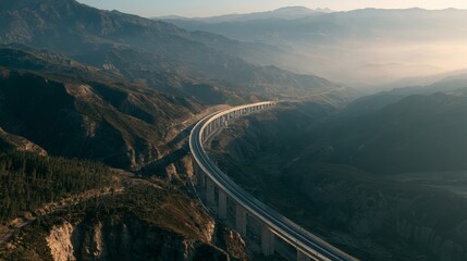 Fototapeta premium Scenic aerial view of winding highway through mountainous landscape at sunset