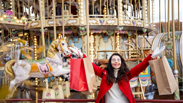 Joyful woman shopping at Christmas market by carousel