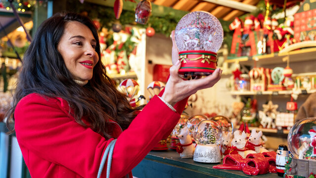 Woman choosing snow globe at Christmas market stall