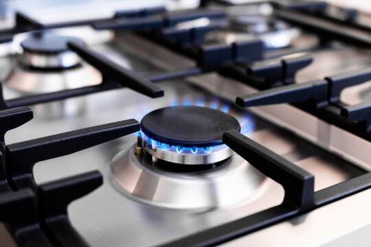 Close-up of gas stove burner with blue flame in kitchen