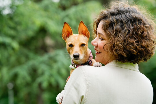 Woman smiling while holding her adopted dog in park