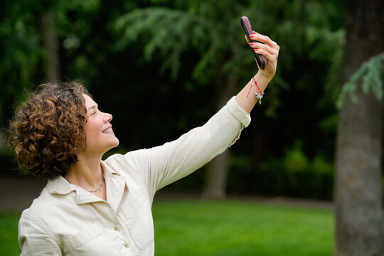 Woman taking selfie in a green park setting