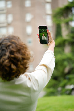 Woman taking selfie in park with smartphone
