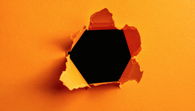 Close up of torn bright orange paper revealing a dark hexagonal shape cutout or hole in the center&nbsp;
