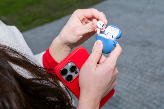 Gen Z woman holding smartphone and wireless earbud case