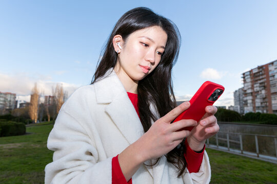 Gen Z Chinese woman using smartphone outdoors in city