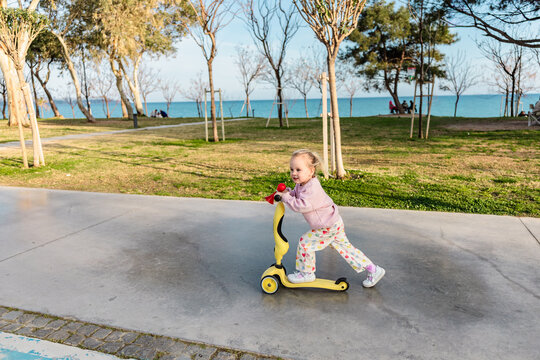 Young child riding scooter on seaside park walkway