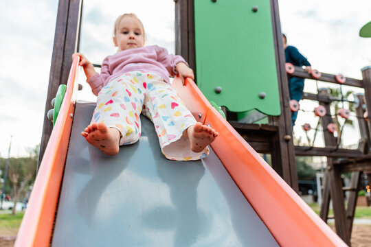 Toddler sliding down playground slide on sunny day outdoors