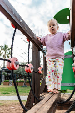 Toddler balancing on playground bridge rope obstacle course
