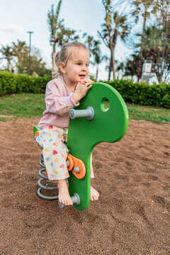 Toddler riding spring rocker toy at outdoor playground