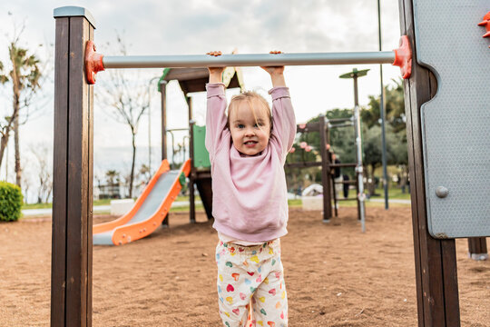 Child hanging from playground bar during outdoor playtime