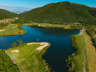 Naklejka premium Golf course island green surrounded by lake and hills aerial