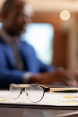 Eyeglasses rest on clipboard files at a startup office desk, suggesting project planning, marketing strategy and professional paperwork, linking business glasses and office paperwork.