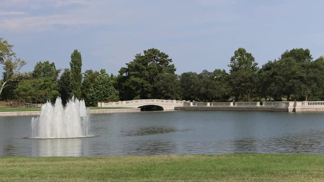 Fountain and bridge over pond in park.